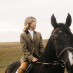Young Woman Riding a Black Horse in an Open Countryside Landscape